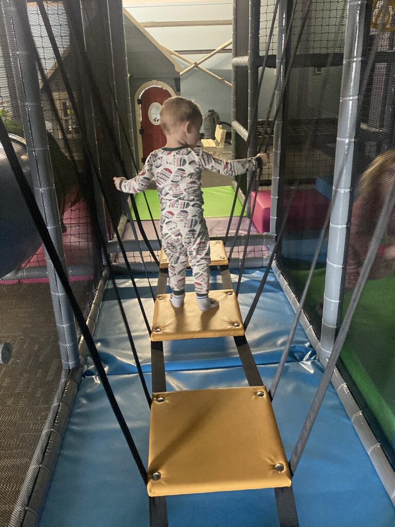A child crossing a suspension bridge inside the indoor playground for kids at Nugget Nation MKE