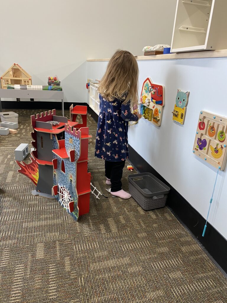 A child playing with the interactive toys in the Nugget Square fine motor play area